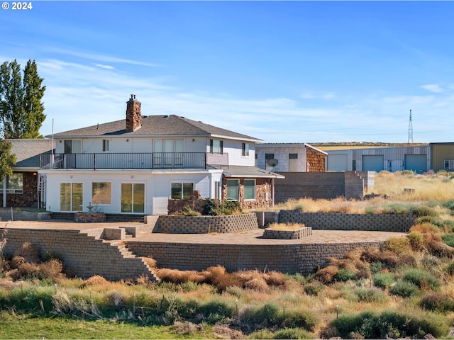 rear view of house featuring a balcony and a patio