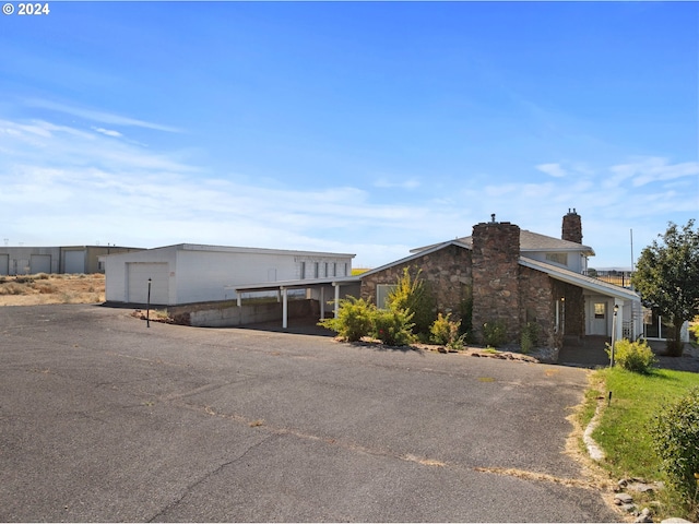 view of side of home with driveway, a chimney, a garage, and concrete block siding
