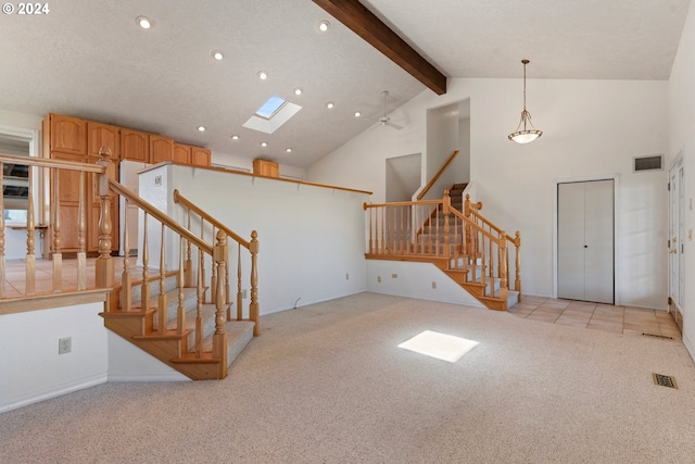 entryway featuring light carpet, a skylight, beamed ceiling, and a textured ceiling