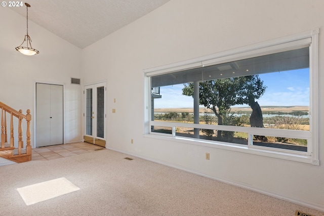 spare room with high vaulted ceiling, stairway, baseboards, light colored carpet, and visible vents