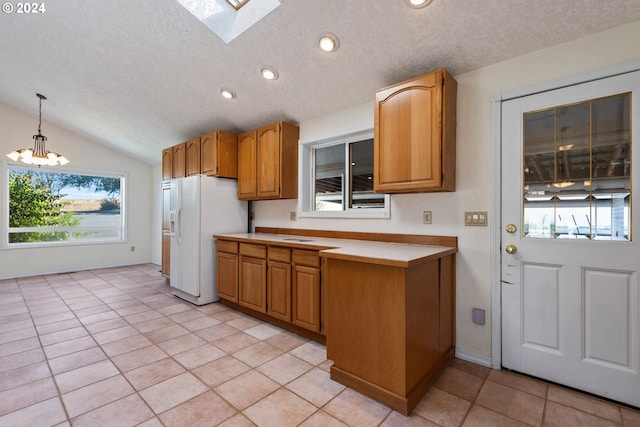 kitchen with vaulted ceiling with skylight, white fridge with ice dispenser, light tile patterned floors, and decorative light fixtures