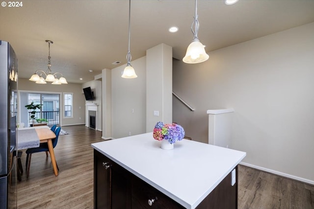 kitchen with a center island, a notable chandelier, hardwood / wood-style floors, pendant lighting, and dark brown cabinets