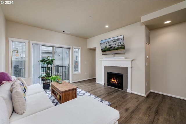 living room with a tiled fireplace and dark hardwood / wood-style floors