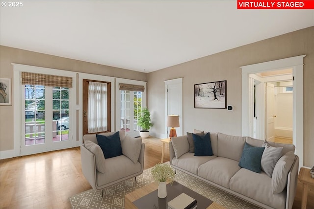 living room with light wood-type flooring, a wealth of natural light, and french doors