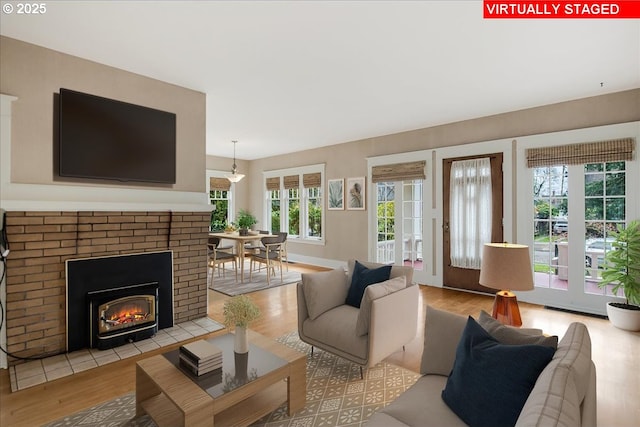 living room with a brick fireplace and light wood-style flooring