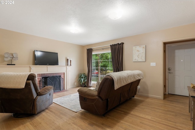 living room featuring a fireplace, a textured ceiling, and light hardwood / wood-style floors