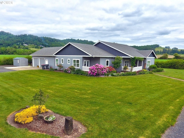 view of front of house with board and batten siding, a front lawn, a garage, and an outdoor structure