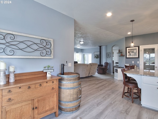 living room with a wood stove, a textured ceiling, and light hardwood / wood-style flooring