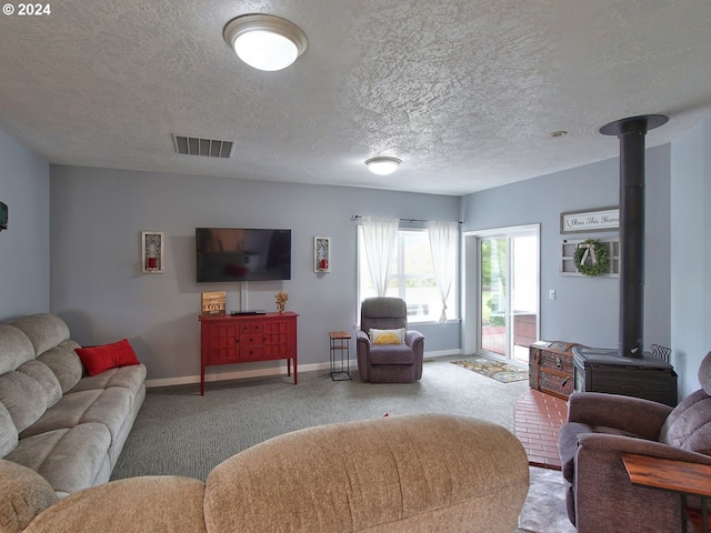 living room featuring carpet flooring, a wood stove, and a textured ceiling