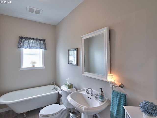 bathroom featuring a bathing tub, toilet, sink, and hardwood / wood-style floors