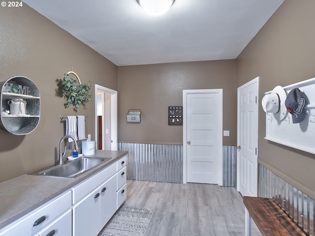 kitchen with white cabinets, light hardwood / wood-style flooring, and sink