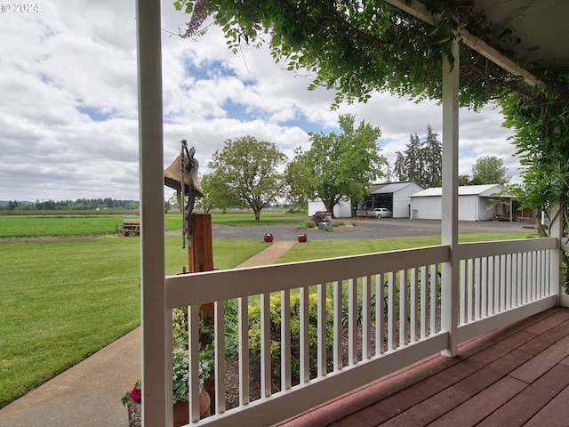 deck with a lawn, a porch, and a rural view