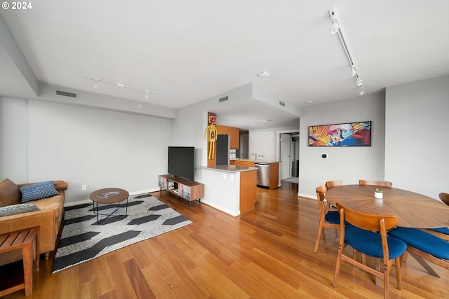 living room featuring light wood finished floors, baseboards, visible vents, and track lighting