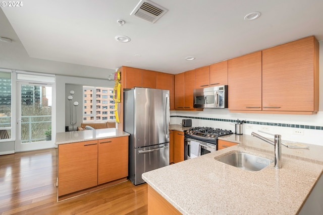 kitchen featuring visible vents, decorative backsplash, appliances with stainless steel finishes, a peninsula, and a sink