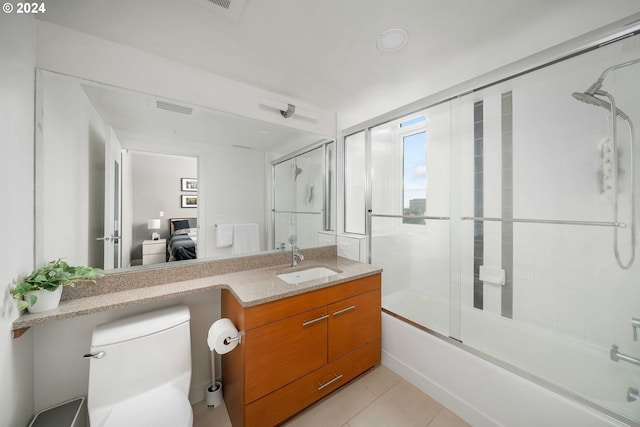 ensuite bathroom featuring toilet, shower / bath combination with glass door, ensuite bath, tile patterned floors, and vanity