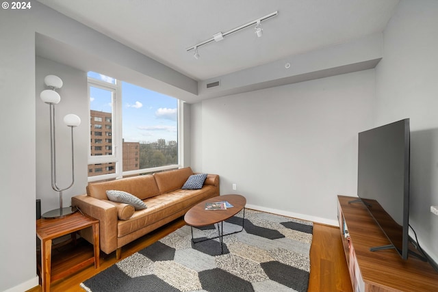 living area with baseboards, track lighting, visible vents, and wood finished floors