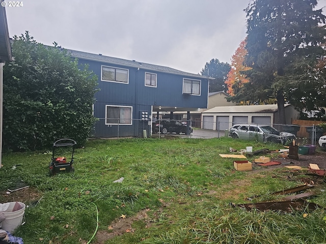 rear view of house featuring an outdoor structure, a garage, and a lawn