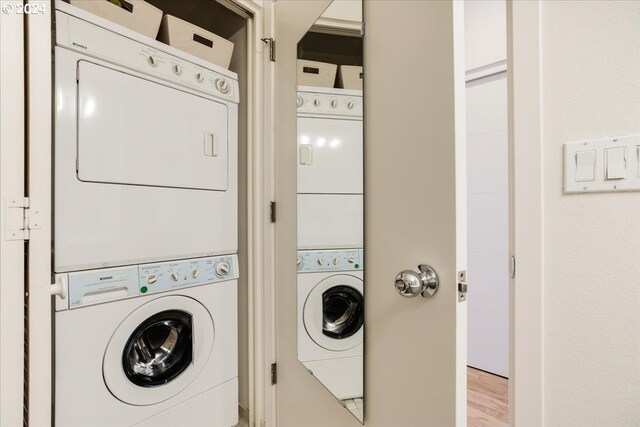 laundry room featuring stacked washer and clothes dryer and light wood-type flooring