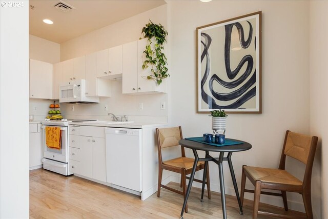 kitchen with white appliances, light hardwood / wood-style floors, and white cabinetry