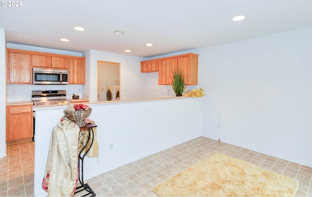 kitchen featuring stainless steel appliances, washing machine and dryer, and kitchen peninsula