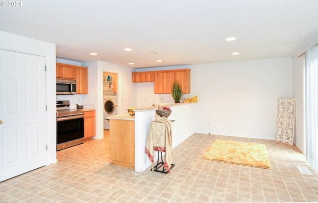 kitchen featuring washer / clothes dryer, kitchen peninsula, and appliances with stainless steel finishes