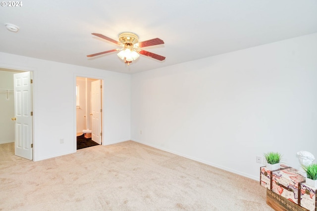 unfurnished bedroom with connected bathroom, carpet floors, a walk in closet, ceiling fan, and a closet