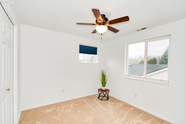 spare room featuring plenty of natural light, light carpet, and ceiling fan