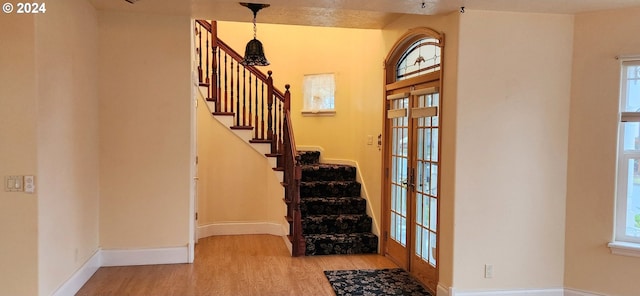 stairway featuring hardwood / wood-style flooring, a healthy amount of sunlight, and french doors