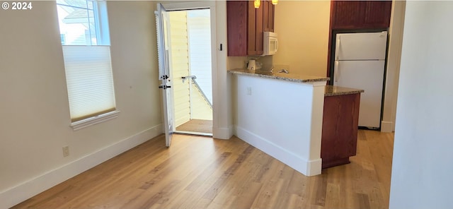 kitchen with light stone countertops, white appliances, and light hardwood / wood-style flooring