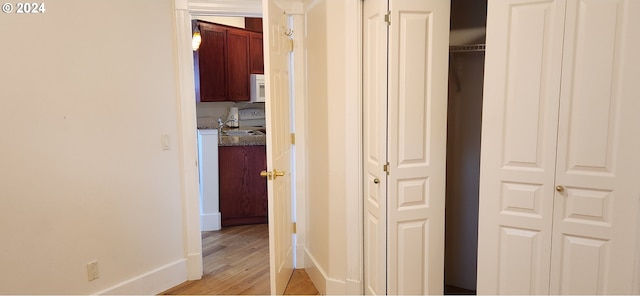 corridor with sink and light hardwood / wood-style flooring