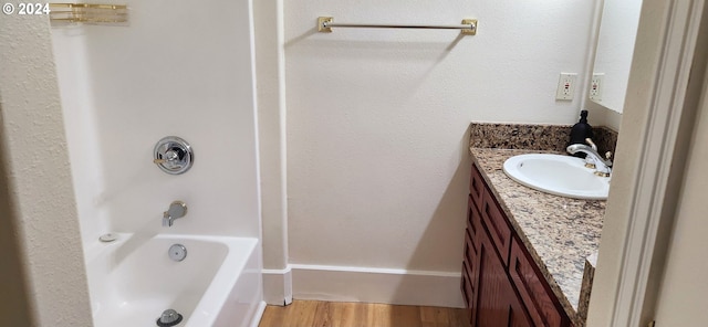 bathroom with washtub / shower combination, wood-type flooring, and vanity