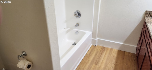 bathroom with hardwood / wood-style floors, vanity, and washtub / shower combination