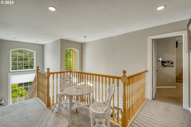 hallway with light carpet and a textured ceiling