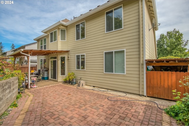 rear view of property featuring a pergola and a patio