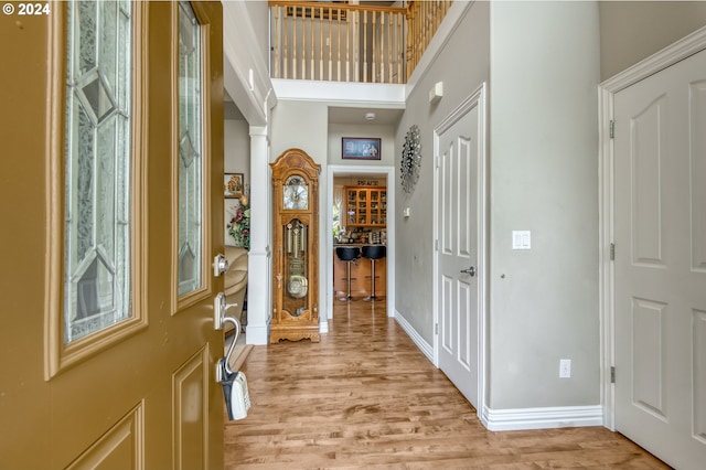 foyer entrance with light wood-type flooring and a towering ceiling