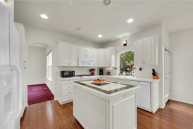 kitchen featuring white cabinetry, hardwood / wood-style flooring, a kitchen island, and white appliances