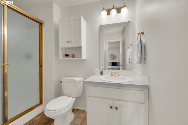 bathroom featuring vanity, toilet, and a shower with shower door