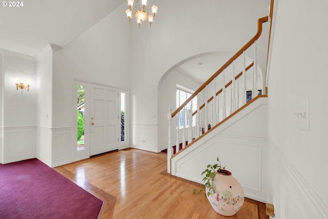 entrance foyer with a notable chandelier, ornamental molding, light hardwood / wood-style flooring, and a high ceiling