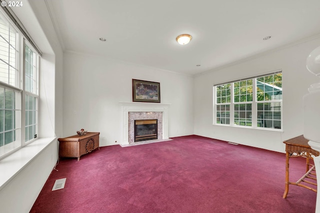 unfurnished living room featuring a high end fireplace, carpet, and crown molding