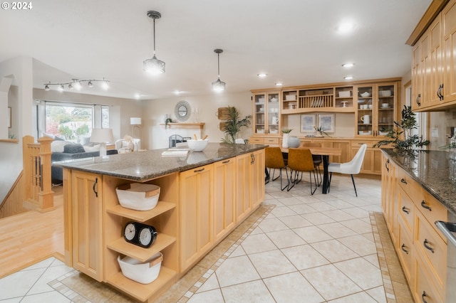 kitchen featuring pendant lighting, light brown cabinets, dark stone countertops, light tile patterned floors, and a kitchen island