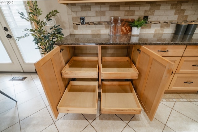 details with decorative backsplash, light brown cabinetry, and dark stone counters