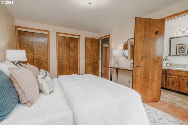 bedroom featuring sink, light hardwood / wood-style floors, and two closets