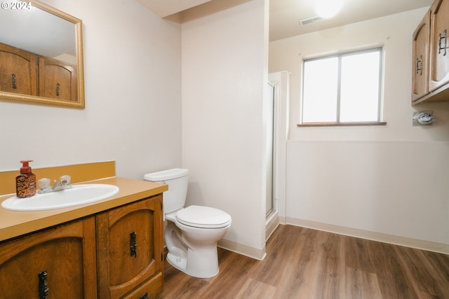 bathroom featuring hardwood / wood-style floors, vanity, toilet, and a shower with door