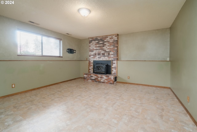 unfurnished living room with a wood stove and a textured ceiling