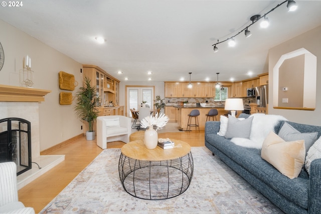 living room with a tile fireplace and light hardwood / wood-style flooring