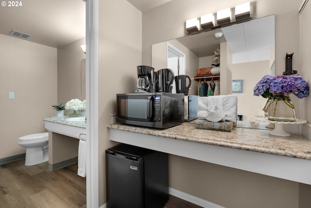 bathroom with visible vents, toilet, vanity, wood finished floors, and baseboards