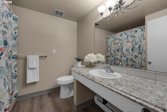 bathroom featuring visible vents, toilet, vanity, wood finished floors, and baseboards