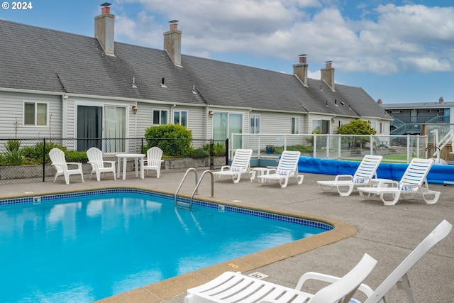 community pool with a patio and fence