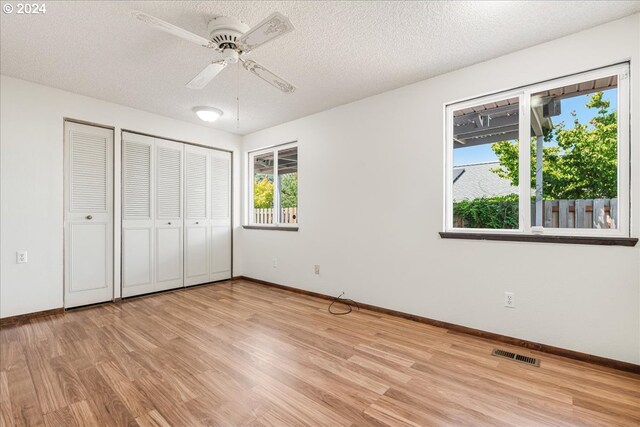 unfurnished bedroom with ceiling fan, light wood-type flooring, and a textured ceiling