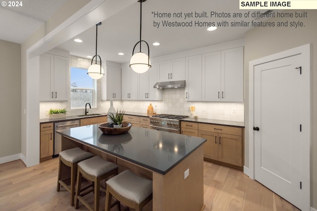 kitchen with stainless steel appliances, sink, pendant lighting, white cabinets, and a center island